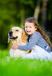 Little girl sitting on the grass with labrador 